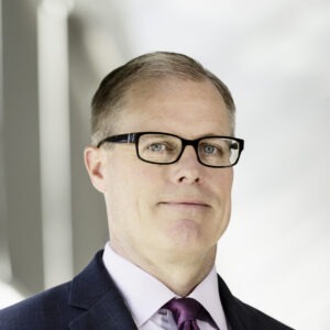 headshot of man in glasses smiling