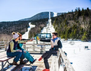 three people clinking glasses at ski lodge