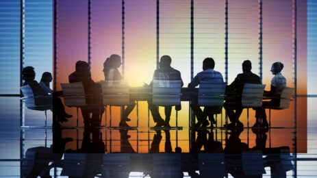 silhouette of seven people talking in boardroom