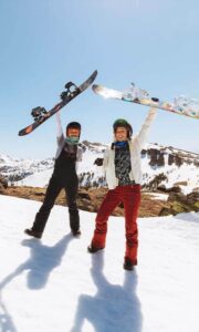 two people holding snowboards on mountain