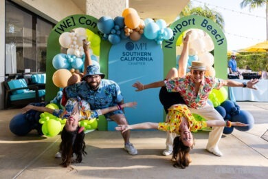 two pairs of colorfully dressed people spreading arms at entrance to WeCon Southern California