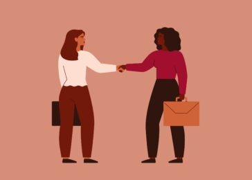 Businesswomen shake hands and look at each other
