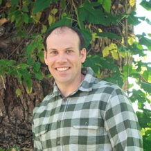 man in green plaid long sleeve dress shirt smiling profile photo