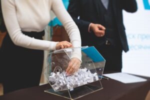 woman putting hand in clear case full of raffle tickets