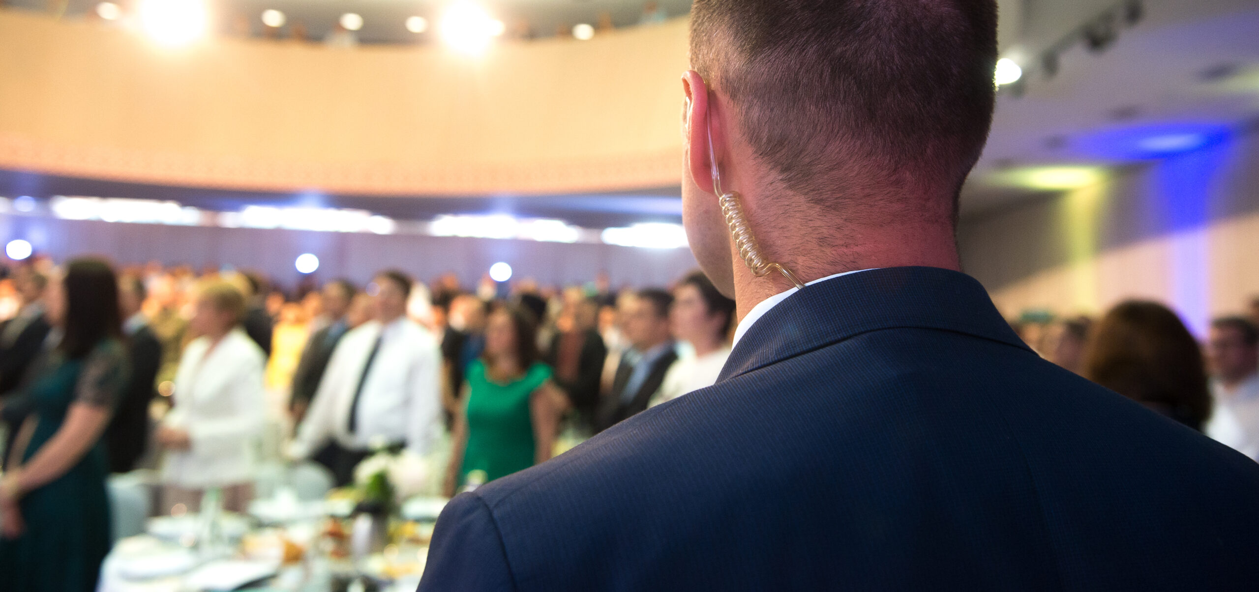 Private bodyguard with earpiece standing among crowd