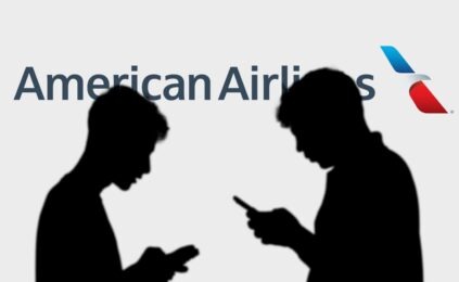 silhouettes of two people on smartphones standing in front of American Airlines logo