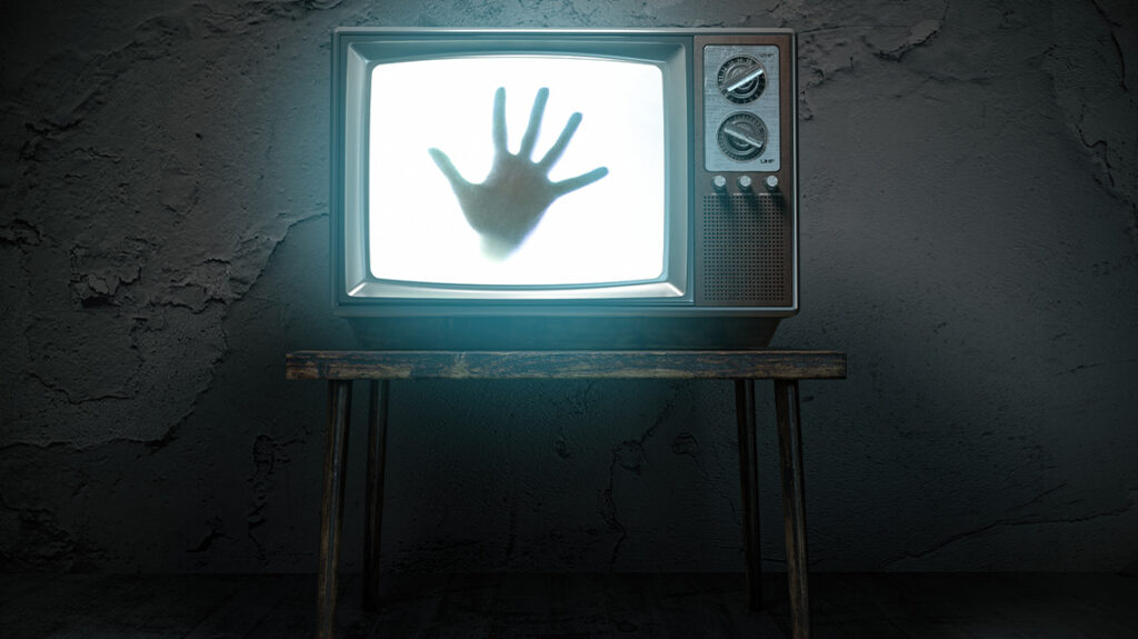 Hand of ghost on screen of vintage tv in haunted house