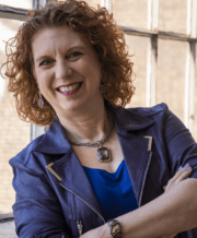 Lisa Ryan in blue shirt and blue coat folding arms profile photo