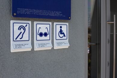 Set of symbols with braille text on special sign near the entrance to a building