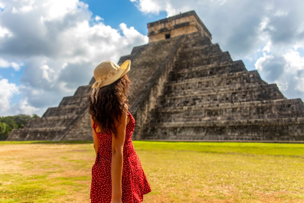 Woman in red dress standing in front of Chichen Itza temple in Mexico