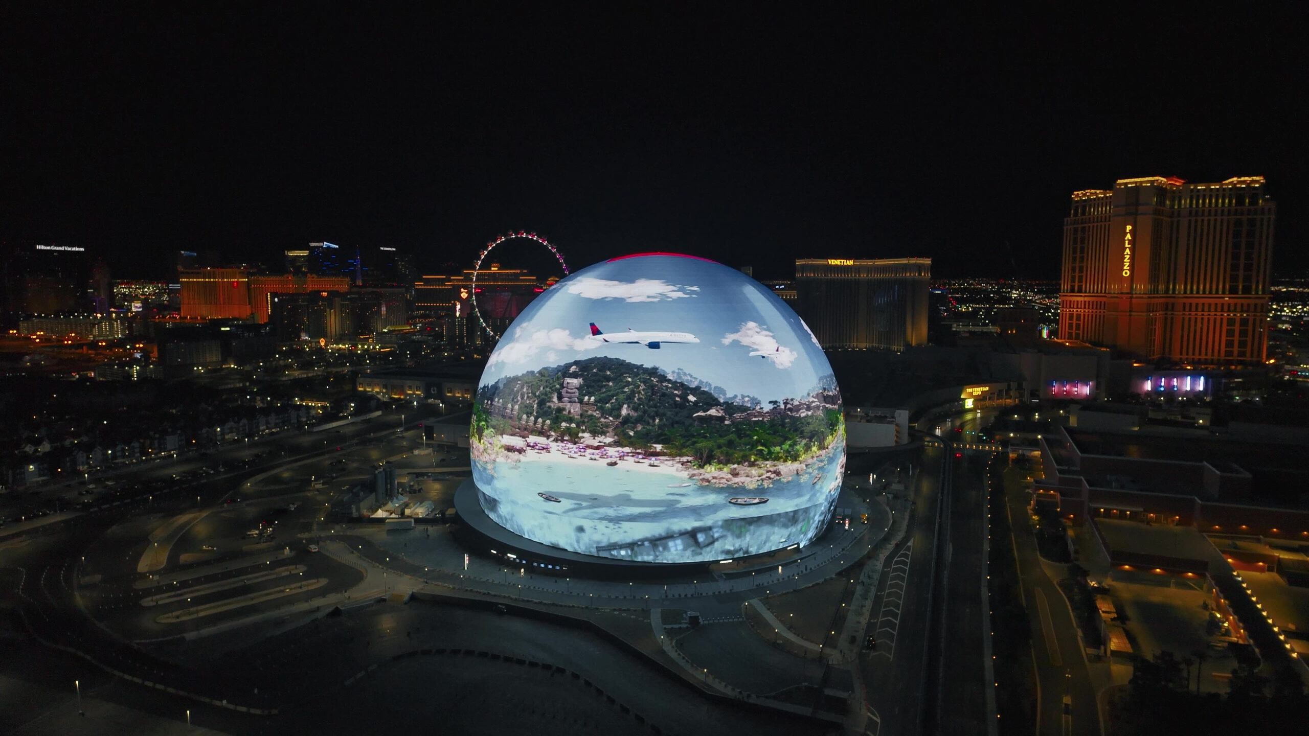 Aerial of blue Sphere exterior in Las Vegas displaying airplane flying over beach