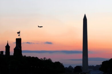 Plane flying over the Smithsonian Institution, the National Mall and Washington Memorial at dusk in downtown Washington DC