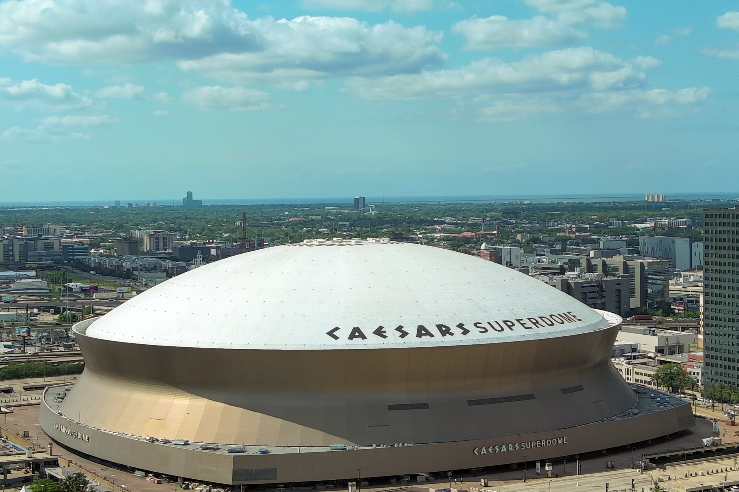 Aerial shot of the Caesars Superdome with skyscrapers, office buildings and hotels in the city skyline and cars on the street in New Orleans