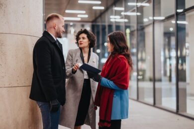 three businesspeople in winter coats talking in office