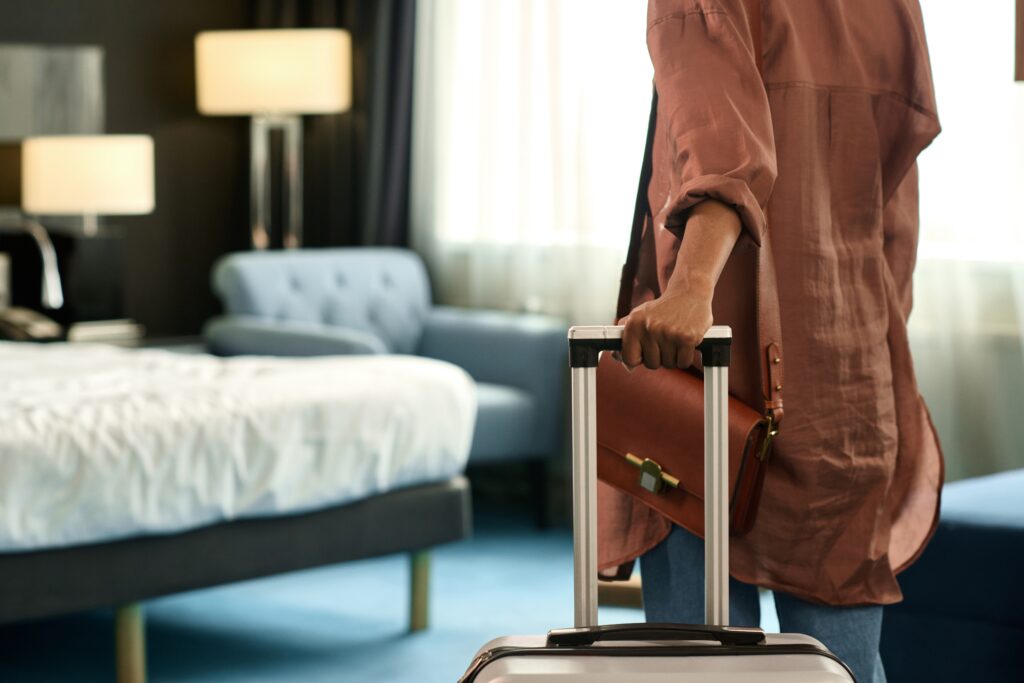 Close up of woman entering hotel room and holding suitcase