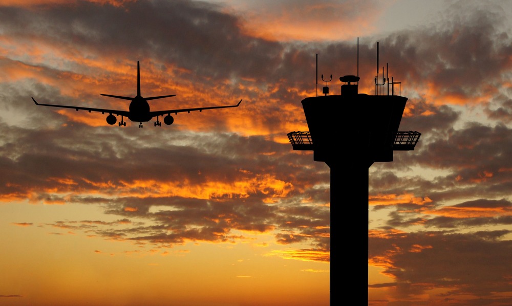 Silhouetted airplane and air traffic control tower at dawn